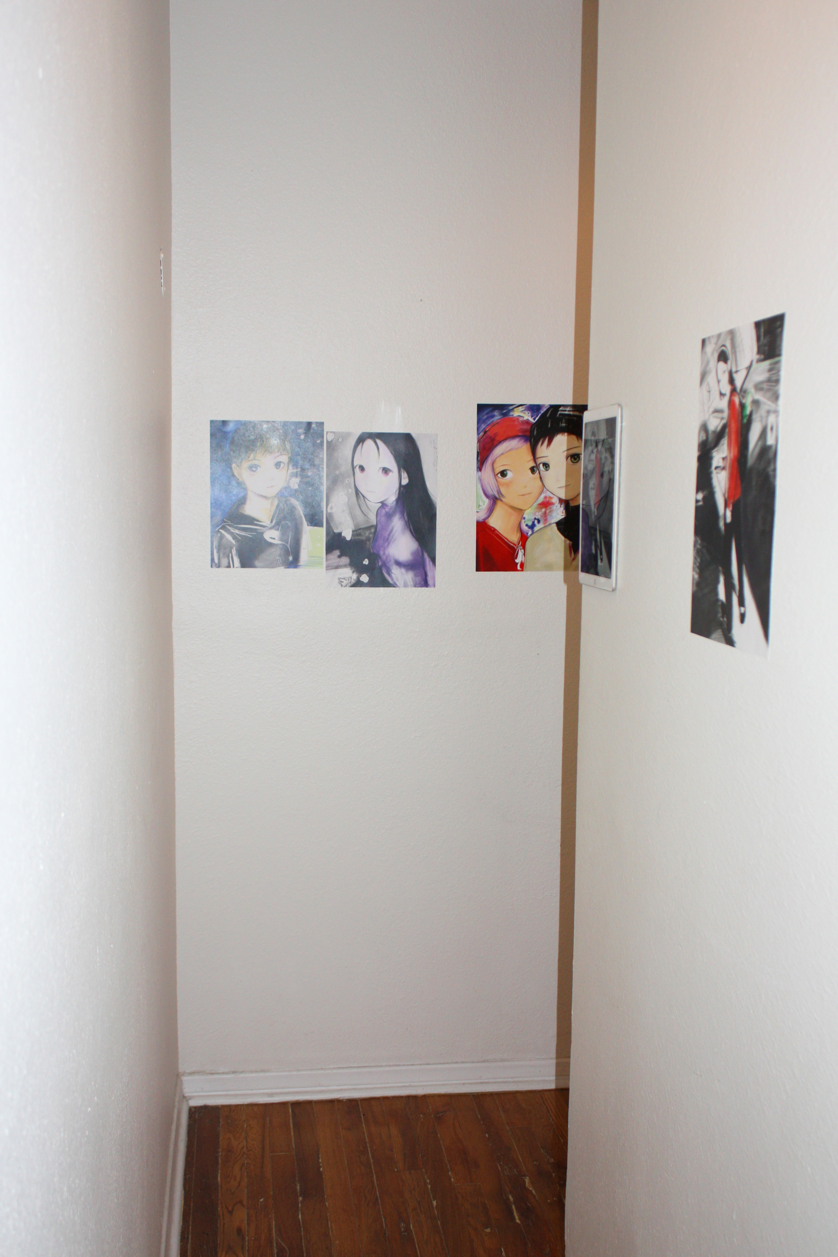 The corner of a hallway with four prints and an iPad hung on the walls
